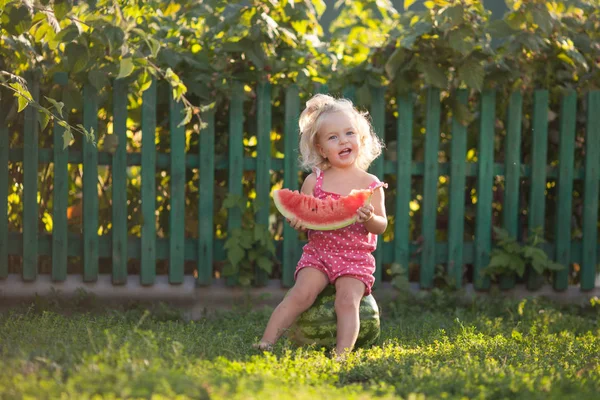 Happy Little Girl jest jedzenie arbuz w ogrodzie letnim, na zewnątrz. — Zdjęcie stockowe