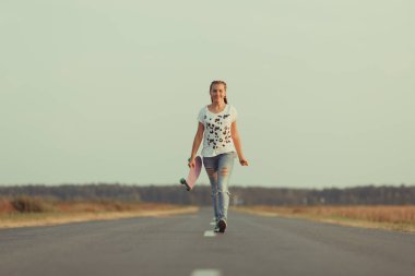 Genç mutlu sevimli kız yolda açık kaykay sürmek