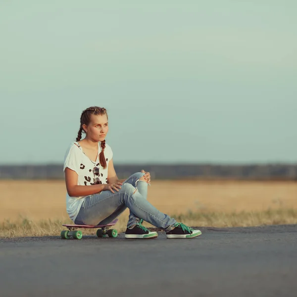 Молодая счастливая милая девушка ездит на скейтборде по дороге, на открытом воздухе — стоковое фото