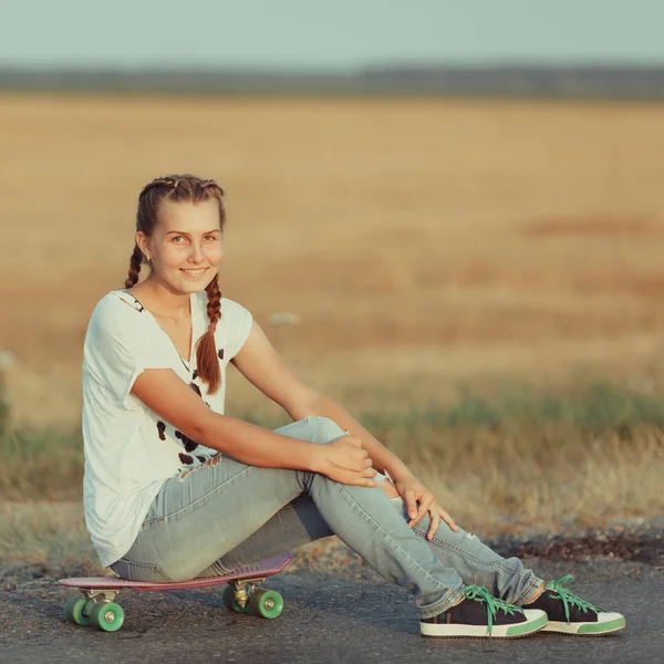 Jovem feliz bonito menina passeios de skate na estrada, ao ar livre — Fotografia de Stock