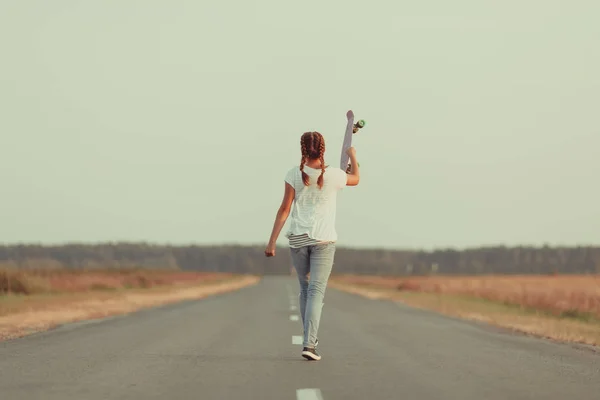 Young happy cute girl rides skateboard on road, outdoor — Stock Photo, Image