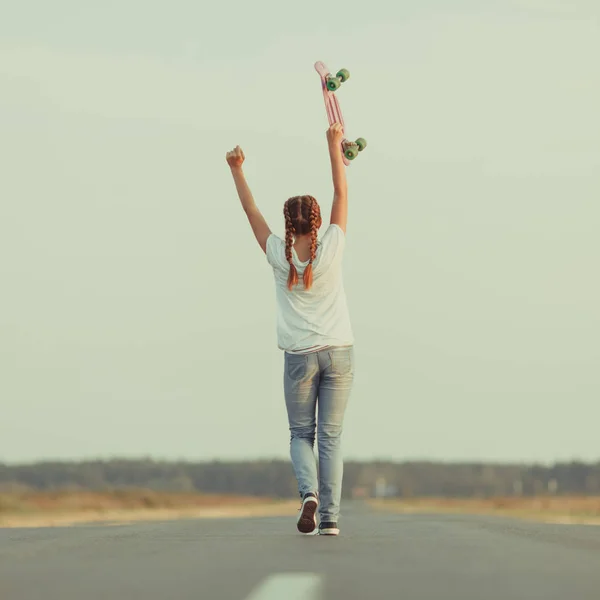 Jovem feliz bonito menina passeios de skate na estrada, ao ar livre — Fotografia de Stock