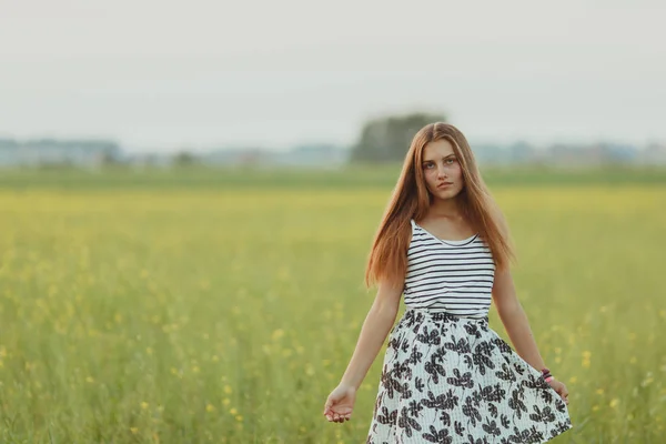 Retrato de una hermosa niña en un campo con flores amarillas, verano, puesta de sol —  Fotos de Stock