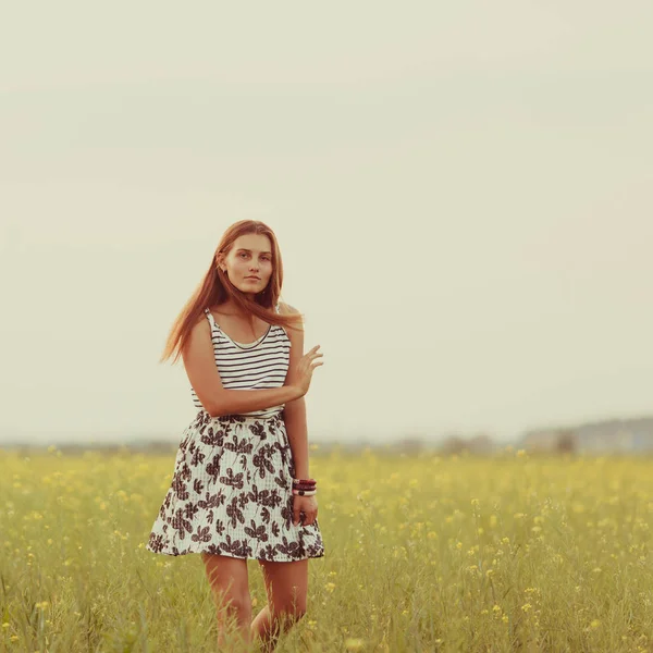 Portrét nádherné dívky na poli se žlutými květy, léto, západ slunce — Stock fotografie