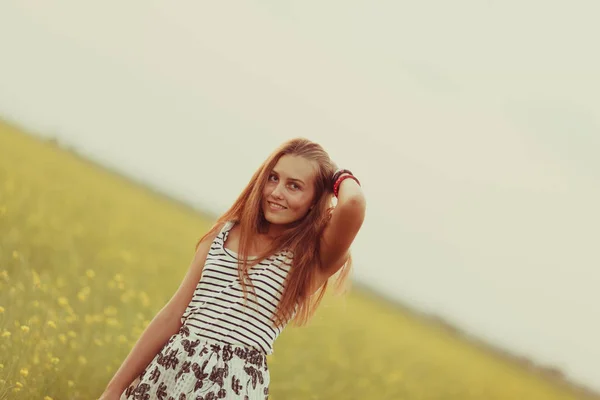 Portrét nádherné dívky na poli se žlutými květy, léto, západ slunce — Stock fotografie