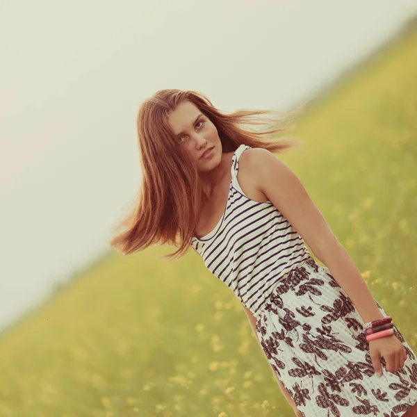 Портрет красивой девушки в поле с желтыми цветами, летом, закатом — стоковое фото