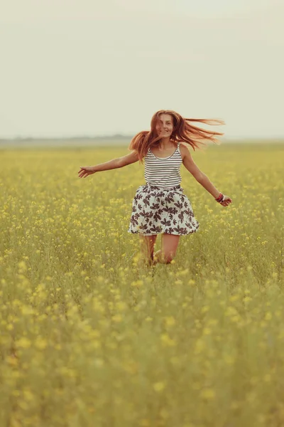 Portré egy gyönyörű lány egy olyan területen, sárga virágok, nyár, naplemente — Stock Fotó