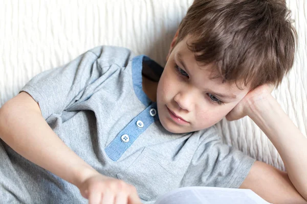 Junge liest ein Buch auf der Couch im Zimmer — Stockfoto