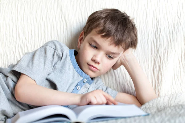 Chico leyendo un libro en el sofá de la habitación — Foto de Stock