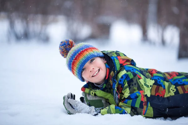 Веселый счастливый мальчик играет в зимнем парке, на открытом воздухе — стоковое фото