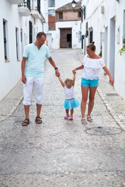 Family vacation in Europe. parents and daughter at street of typical spain traditional village.