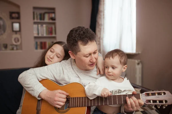 Retrato de una gran familia, niños y padres cantan y tocan la guitarra juntos, en interiores —  Fotos de Stock