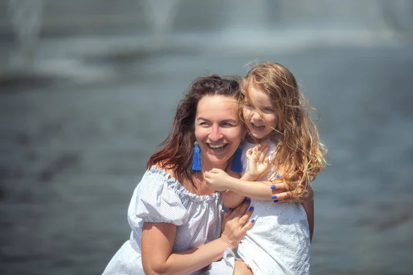 Mãe e filha felizes andando perto da fonte — Fotografia de Stock