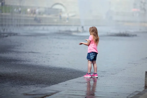 Kleines nettes Mädchen zu Fuß in der Nähe des Brunnens, im Freien — Stockfoto