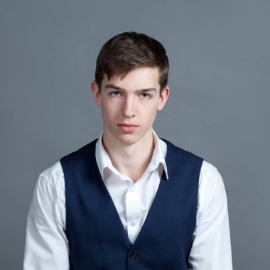 Beyaz gömlek ve ceket gri arka plan karşı mutlu okul çocuğu genç portresi