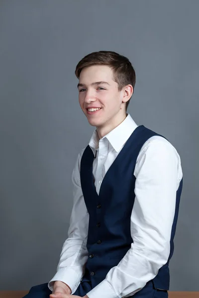 Retrato de adolescente colegial feliz en camisa blanca y chaqueta sobre fondo gris — Foto de Stock