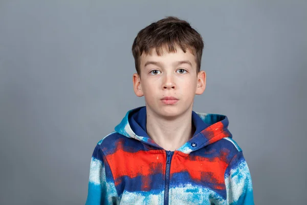 Porträt eines ernsthaften Teenagers in einem farbigen Pullover auf grauem Hintergrund — Stockfoto