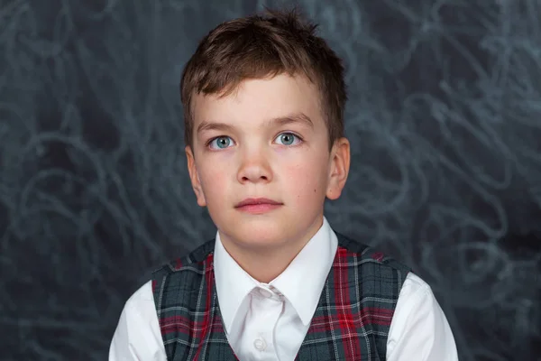 Portret van serieuze gelukkige kleine school kind op achtergrond van back Board op school, indoor. — Stockfoto