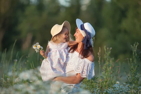 Happy family mother with cute little child girl in the romomile field in summer — стоковое фото