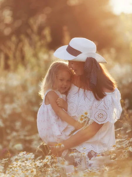 Feliz familia madre con linda niña en el campo de manzanilla en verano —  Fotos de Stock