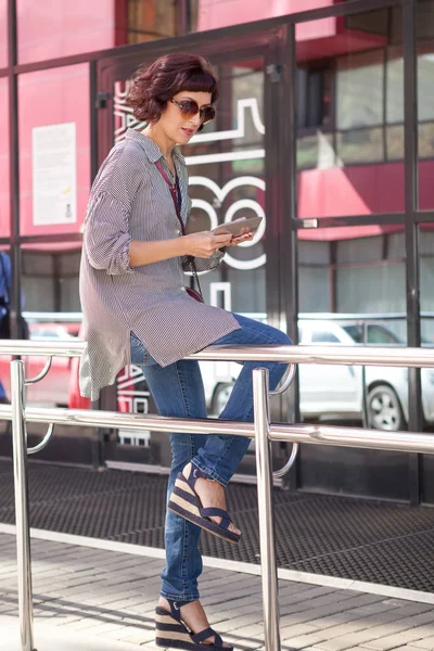 Güzel bir kadın yürüyüş ve güneşli bir yaz gününde sokakta bir akıllı telefon kullanarak — Stok fotoğraf