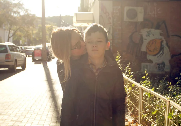 Mother with son on sundown. Mother kissing her son on the cheek