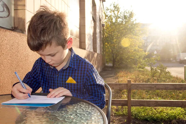 Wrtitting 的东西 男孩在户外做作业 男孩在纸上画画或 Wrtitting 一封信 — 图库照片