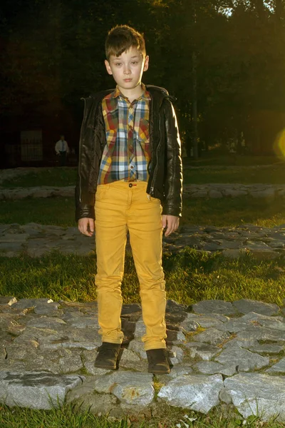 时尚的男孩站在秋天的公园里 男孩在黑色夹克和黄色裤子 — 图库照片