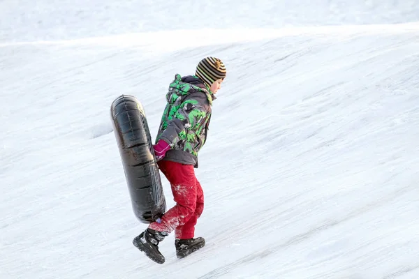 Happy boy with snow tube. Winter fun. Sliding down the hill on a snow tube