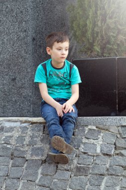 Açık havada yere oturmuş çocuk