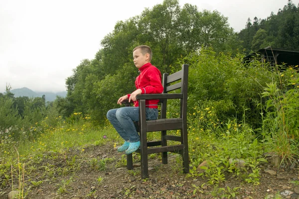 Chlapce, který seděl na židli v lese — Stock fotografie