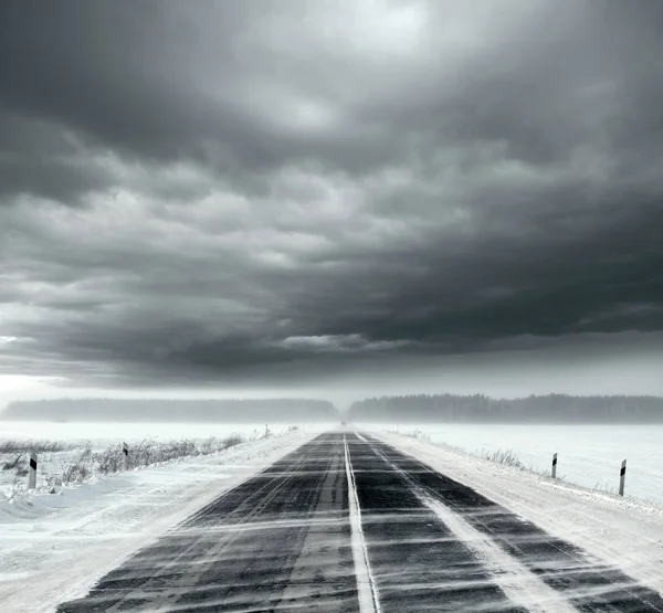 Céu tempestuoso e estrada de neve — Fotografia de Stock