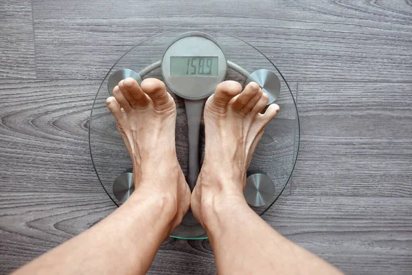 Image of human feet standing on electronic scales, on gray background, top view, diet concept