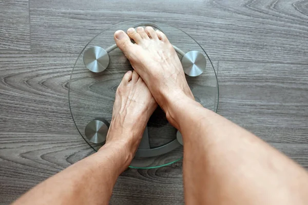 Image of human feet standing on electronic scales, on gray background, top view, diet concept