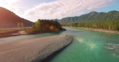 4k UHD hava görüntüsü. Güneşli yaz sabahında taze soğuk dağ nehri üzerinde alçak uçuş. Horisont 'ta yeşil ağaçlar ve güneş ışınları