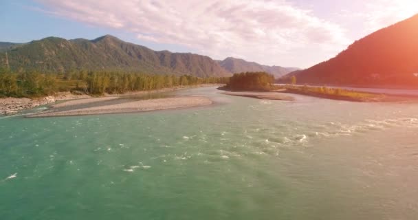 4k UHD aerial view. Low flight over fresh cold mountain river at sunny summer morning. Green trees and sun rays on horisont — Stock Video