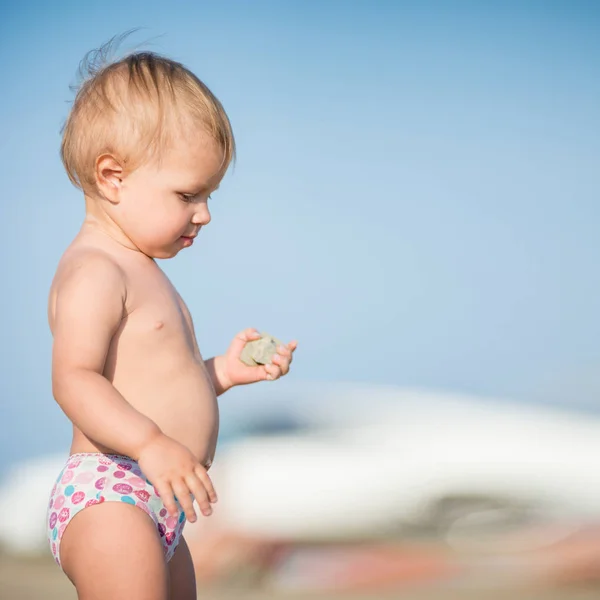 Carino bambino che gioca con i giocattoli sulla spiaggia di sabbia vicino al mare . — Foto Stock