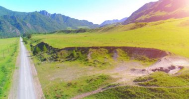 Güneşli yaz sabahında havadan kırsal dağ yolu ve çayır. Asfalt karayolu ve nehir.