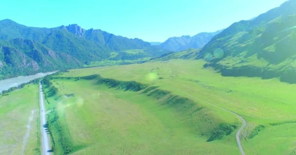 Luchtfoto landelijke bergweg en weide op zonnige zomerochtend. Asfaltweg en rivier. — Stockvideo