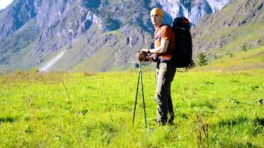 Sırt çantası ile yeşil dağ çayır üzerinde yürüyen adam hiking. Yaz spor ve eğlence kavramı.