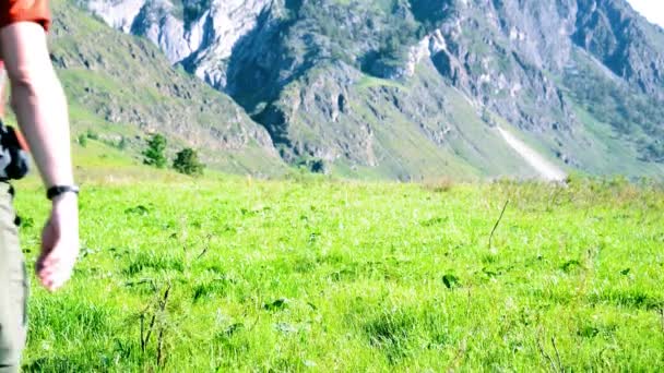 Sırt çantası ile yeşil dağ çayır üzerinde yürüyen adam hiking. Yaz spor ve eğlence kavramı. — Stok video