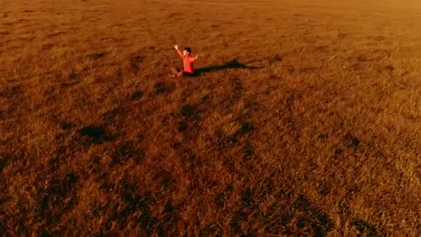 Vuelo radial de baja altitud sobre el hombre del yoga del deporte en hierba verde perfecta. Puesta de sol en montaña. — Vídeo de stock