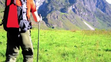 Sırt çantası ile yeşil dağ çayır üzerinde yürüyen adam hiking. Yaz spor ve eğlence kavramı.