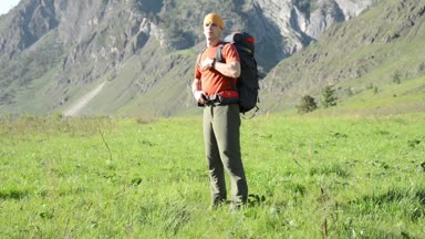 Sırt çantası ile yeşil dağ çayır üzerinde yürüyen adam hiking. Yaz spor ve eğlence kavramı.