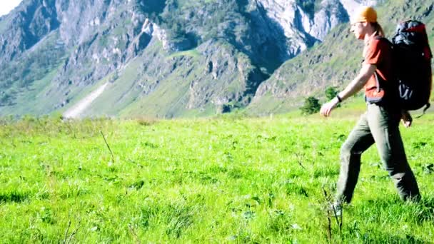 Wandersmann auf der grünen Bergwiese mit Rucksack. Sommersport- und Freizeitkonzept. — Stockvideo