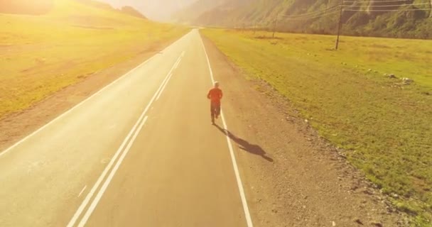 Vol à basse altitude devant un sportif sur une route asphaltée parfaite — Video