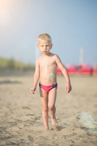 Милый мальчик, гуляющий по песчаному пляжу у моря. Берег океана . — стоковое фото