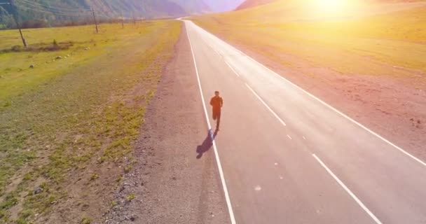 Volo a bassa quota di fronte all'uomo sportivo in perfetta strada asfaltata — Video Stock