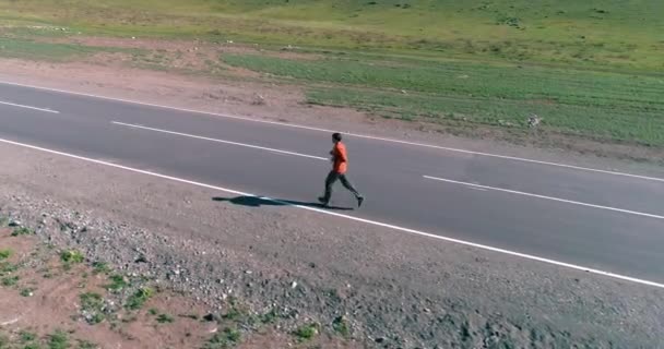 Vuelo de baja altitud frente al deportista en el camino perfecto de asfalto — Vídeo de stock