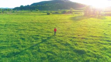 Mükemmel yeşil çayır üzerinde uçan bir sporcu. Dağda gün batımı